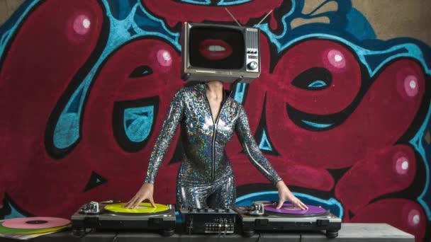 Mujer con tv en la cabeza djing y bailando contra el graffiti
  - Imágenes, Vídeo