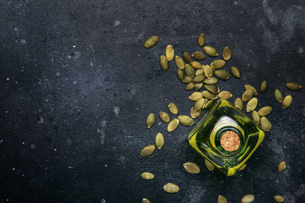 Light pumpkin seeds oil in glass jar on gray kitchen table background, top view - Foto, immagini