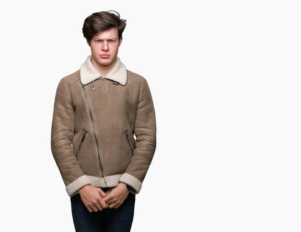 Jonge knappe man dragen winterjas over geïsoleerde achtergrond scepticus en nerveus, fronsen boos vanwege probleem. Negatief persoon. - Foto, afbeelding
