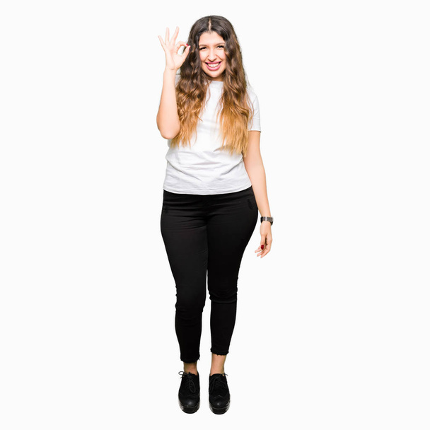 Young beautiful woman wearing casual white t-shirt smiling positive doing ok sign with hand and fingers. Successful expression. - Foto, Imagem
