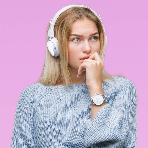 Молода біла жінка слухає музику в навушниках над ізольованим тлом, виглядає напруженою і нервує руками на роті, кусаючи нігті. Проблема тривоги
. - Фото, зображення