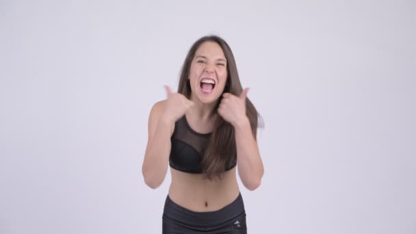 Young happy woman giving thumbs up and looking excited ready for gym - Séquence, vidéo