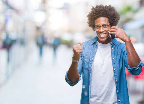 Hombre afroamericano hablando por teléfono sobre un fondo aislado gritando orgulloso y celebrando la victoria y el éxito muy emocionado, animando la emoción
 - Foto, imagen