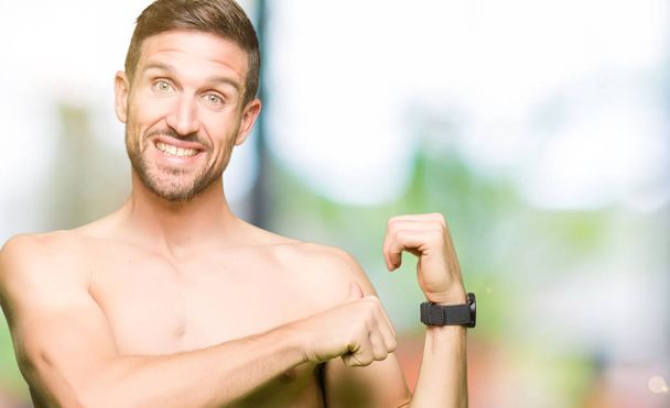 Handsome shirtless man showing nude chest Pointing to the back behind with hand and thumbs up, smiling confident - Photo, Image