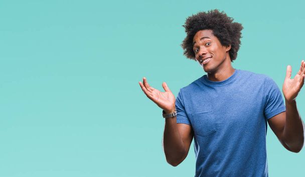 Afro-Amerikaanse man over geïsoleerde achtergrond clueless en verward expressie met armen en handen aan de orde gesteld. Twijfel concept. - Foto, afbeelding