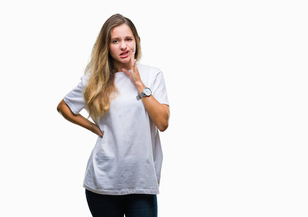 Giovane bella donna bionda indossa casual t-shirt bianca su sfondo isolato toccare bocca con mano con espressione dolorosa a causa di mal di denti o malattia dentale sui denti. Concetto di dentista
. - Foto, immagini