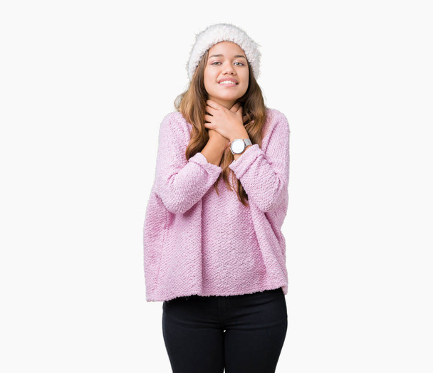 Młoda piękna brunetka kobieta noszenia sweter i czapka zimowa ponad na białym tle krzyku i udusić bo bolesne udusić. Problem zdrowotny. Udusić i koncepcja samobójstwo. - Zdjęcie, obraz