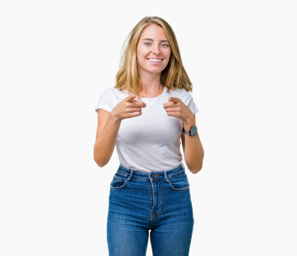 Hermosa mujer joven con camiseta blanca casual sobre fondo aislado señalando los dedos a la cámara con la cara feliz y divertida. Buena energía y vibraciones
. - Foto, Imagen