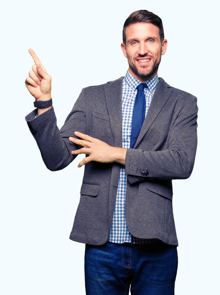 ハンサムなビジネスの男性が身に着けているスーツし、ネクタイの顔に大きな笑みを浮かべてカメラを見ている側の手と指で指す. - 写真・画像