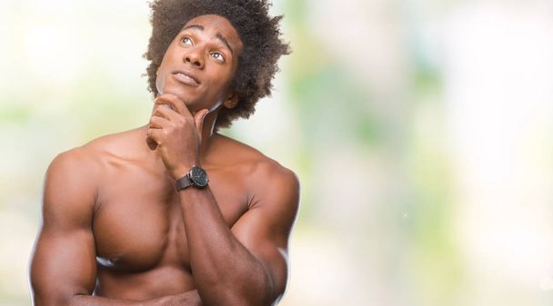 Afro amerikai félmeztelen férfi mutatja a meztelen test felett elszigetelt háttér kézzel a chin gondolkodás kérdés, töprengő kifejezés. Mosolygós, figyelmes arccal. Kétség koncepció. - Fotó, kép