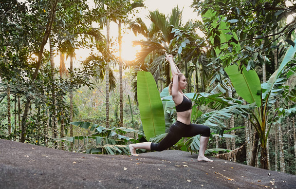 young girl doing yoga at sunset in jungle. Garden - Valokuva, kuva