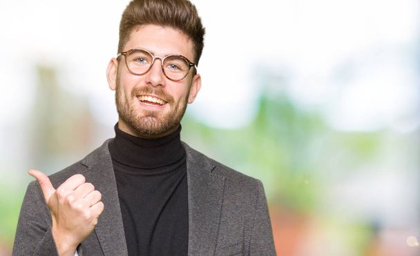 Mladý pohledný obchodní muž nosí brýle dělá šťastné palec nahoru gesto rukou. Schvalování výraz s ukazuje úspěch při pohledu na fotoaparát. - Fotografie, Obrázek