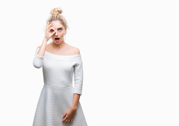 Young beautiful blonde and blue eyes woman over isolated background doing ok gesture shocked with surprised face, eye looking through fingers. Unbelieving expression. - Foto, Bild