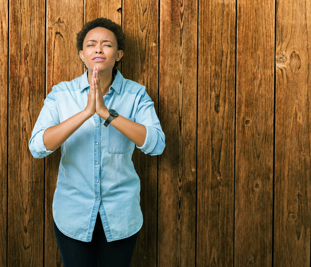 Mladá krásná africká americká žena izolované pozadí prosit a modlit se s rukama naděje výraz na tváři velmi emocionální a strach. Žádá o odpuštění. Pojem náboženství. - Fotografie, Obrázek