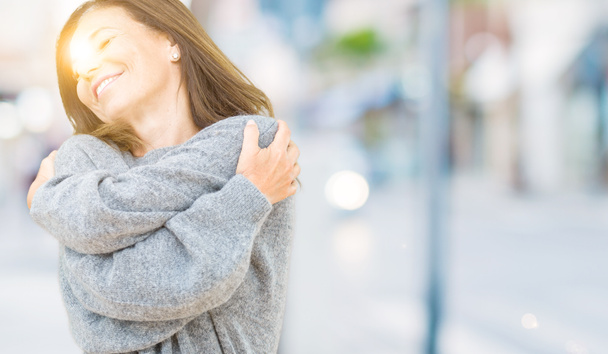 Bella donna di mezza età che indossa maglione invernale su sfondo isolato Abbracciarsi felice e positivo, sorridendo fiducioso. Amore di sé e cura di sé
 - Foto, immagini