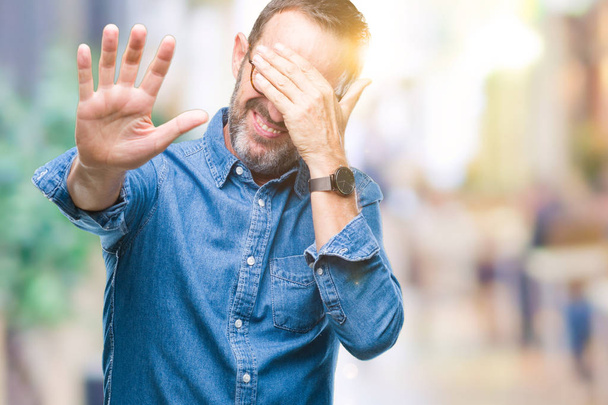 Middle age hoary senior man wearing glasses over isolated background covering eyes with hands and doing stop gesture with sad and fear expression. Embarrassed and negative concept. - Photo, Image