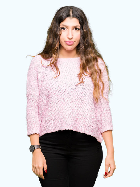 Mujer hermosa joven vistiendo suéter rosa Relajado con expresión seria en la cara. Simple y natural mirando a la cámara
. - Foto, imagen