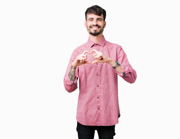 Fiatal jóképű férfi át elszigetelt háttér mosolyogva szerelmes szív szimbólum és a kéz alakú rózsaszín inget visel. Romantikus fogalma. - Fotó, kép