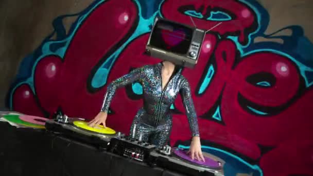 Sexy woman with tv on head djing against graffiti  - Footage, Video