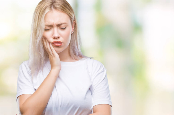 Νεαρή ξανθιά γυναίκα πέρα από το απομονωμένο υπόβαθρο αγγίζοντας το στόμα με το χέρι με επώδυνη έκφραση λόγω πονόδοντος ή οδοντική ασθένεια στα δόντια. Οδοντίατρος έννοια. - Φωτογραφία, εικόνα