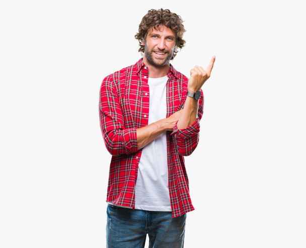 Pohledný hispánský model muž izolované pozadí s velkým úsměvem na tváři, rukou a prstu přejdete na straně při pohledu na fotoaparát. - Fotografie, Obrázek