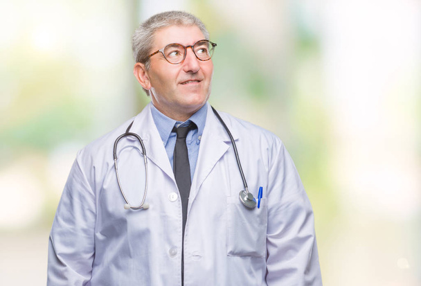 Handsome senior doctor man over isolated background smiling looking side and staring away thinking. - Photo, Image
