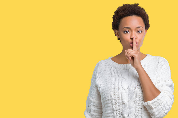 schöne junge afrikanisch-amerikanische Frau trägt Pullover über isoliertem Hintergrund und bittet um Ruhe mit dem Finger auf den Lippen. Schweigen und geheimes Konzept. - Foto, Bild