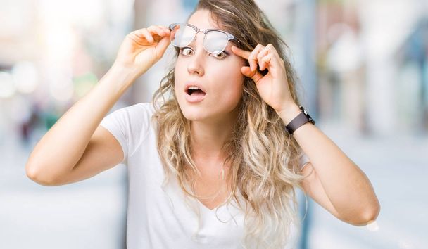 Krásná mladá blond žena nosí brýle izolované pozadí snaží otevřít oči prsty, ospalá a unavená pro ranní únava - Fotografie, Obrázek