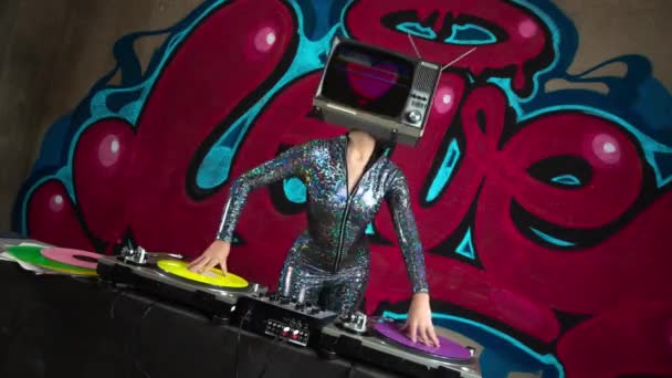 Woman with tv on head djing with graffiti at background - Footage, Video