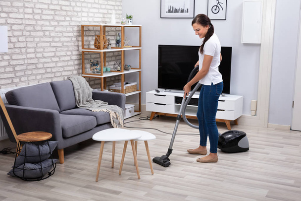 Happy Young Female Janitor Cleaning Floor With Vacuum Cleaner - Zdjęcie, obraz