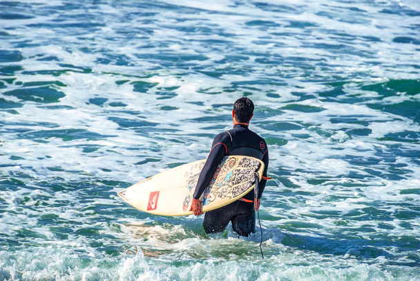 12/18/2018 Netanya, Izrael, surfař s deska jde plavání v oceánu na úsvitu den - Fotografie, Obrázek