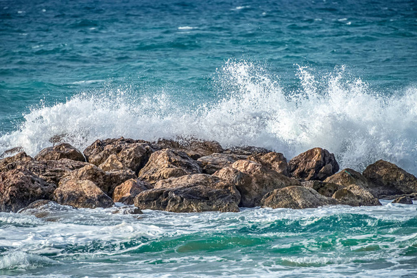onde blu brillante del Mar Mediterraneo sono abbattuti su una passeggiata di cemento in una giornata di sole
 - Foto, immagini