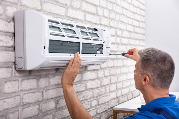 Mature Male Technician Fixing Air Conditioner With Screwdriver - Foto, Bild