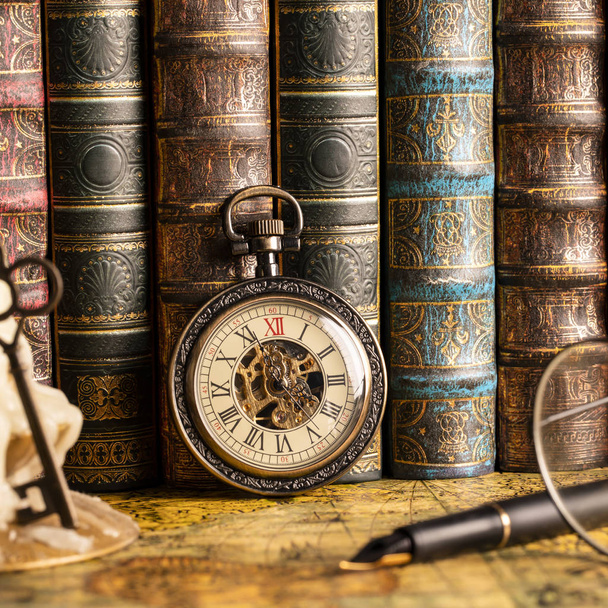 Antique clock on the background of a candle with a key and books. Vintage style. 1565 old map of the year. - Fotó, kép