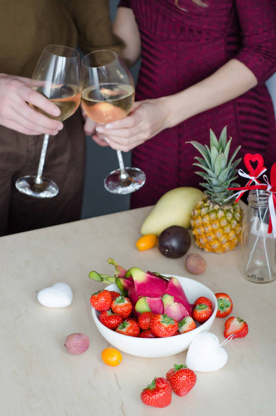 A couple drinking champagne with lying strawberries and exotic fruits. Valentine's Day. Romantic evening - Foto, afbeelding