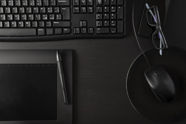 Całkowite czarne biurko z komputerem, tabletem i rzeczami osobistymi - Zdjęcie, obraz