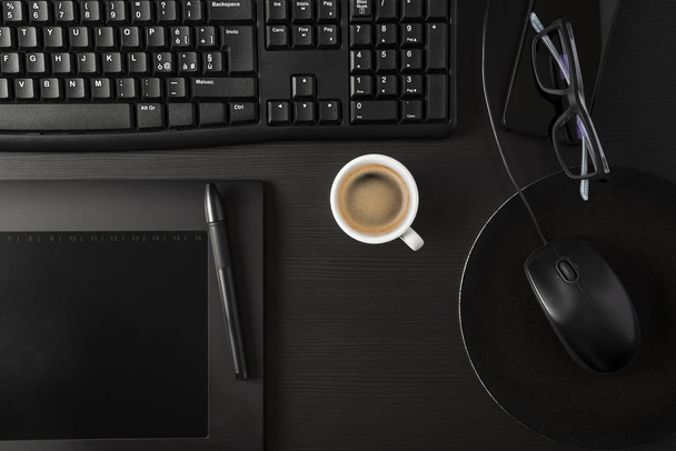 Escritorio negro total con PC, tableta, artículos personales y taza de café
 - Foto, imagen