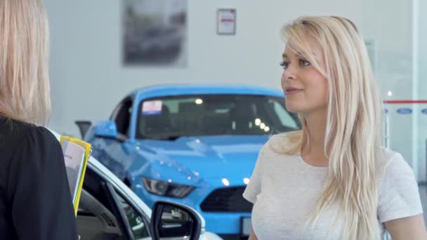 Gyönyörű nő beszél az eladó autó kereskedések szalonban - Felvétel, videó
