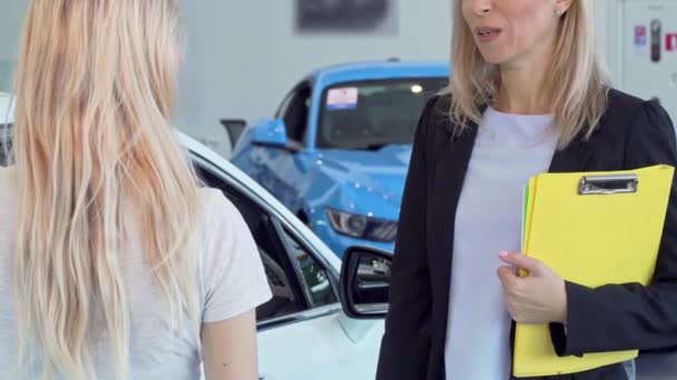 Nainen asiakas vastaanottaa auton avaimet, kättelee myyjä
 - Materiaali, video
