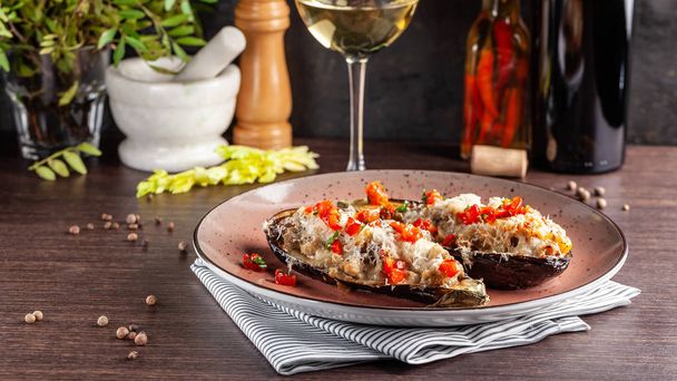 European Spanish cuisine. Baked eggplants with meat and vegetables, parmesan cheese. White wine on the table. Close-up background image. Beautiful serving dishes in the restaurant. - Photo, image