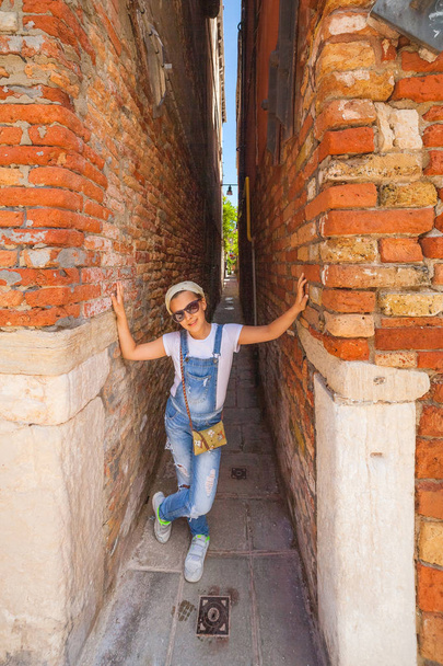 Tourist girl shows how narrow the street is. Venice - Zdjęcie, obraz