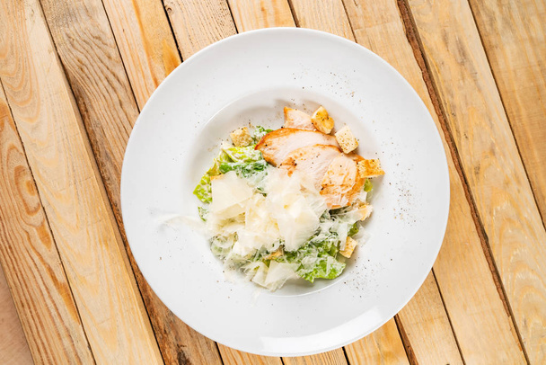 Fresh caesar salad in white plate, wooden background - Foto, Imagem