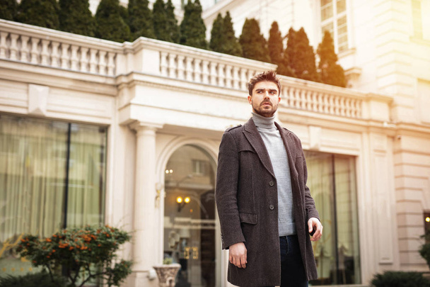 confident and stylish man standing outside in front of a hotel or a nice old building - Фото, зображення