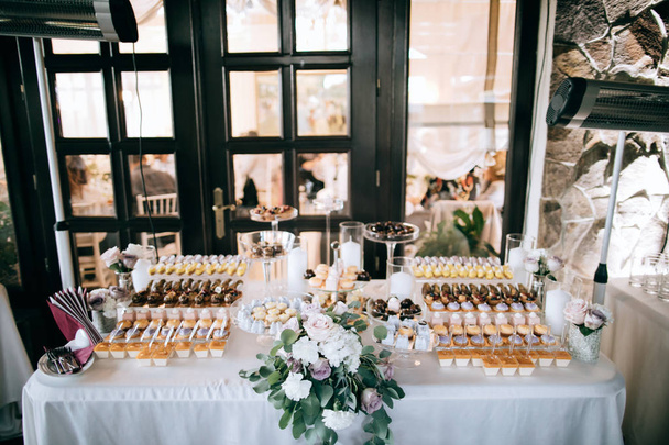 Mesa de postres de boda bellamente decorada con pasteles y echleurs y otros dulces
 - Foto, imagen