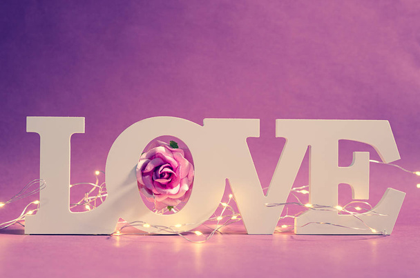 Blanco amor texto madera y luz led con rosa rosa sobre fondo de madera. Concepto Valentine. - Foto, imagen