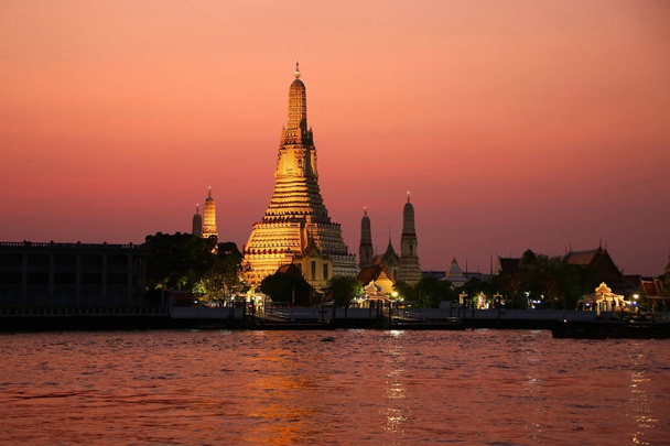 O templo de Dawn or Wat Arun na margem do rio Chao Phrya ao pôr do sol, Bangkok, Tailândia
.  - Foto, Imagem