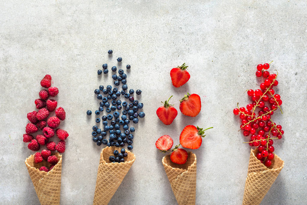 Ice cream cones with fruits. Fresh berry fruit, top view of strawberry, blueberry, raspberry and red currant. - Foto, afbeelding