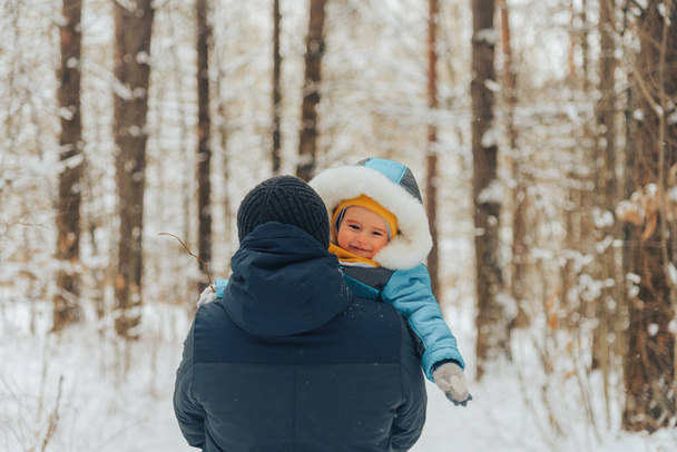 Dad with his son walks in the winter in the woods. Family walks in nature in winter. Winter forest. Snow park. Family vacation. - Foto, afbeelding