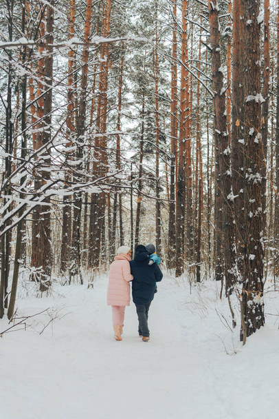 Walking family with a child. Family walks in nature in winter. Winter family walk in nature. A lot of snow. Snowy forest. - Zdjęcie, obraz
