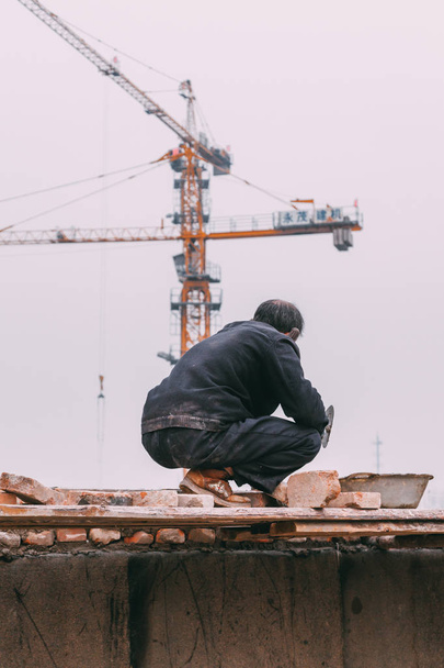 18 dic, 2014 Pekín. un hombre en un sitio de construcción en la ciudad con grúas, tomando Ladrillos un
 - Foto, imagen